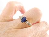 a woman ' s hand holding a ring with a blue stone on it