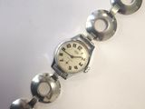 une photo d'une montre-bracelet argentée posée sur une surface blanche