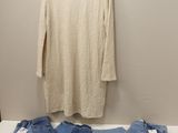 deux paires de jeans et un pull suspendus à un cintre devant un mur blanc