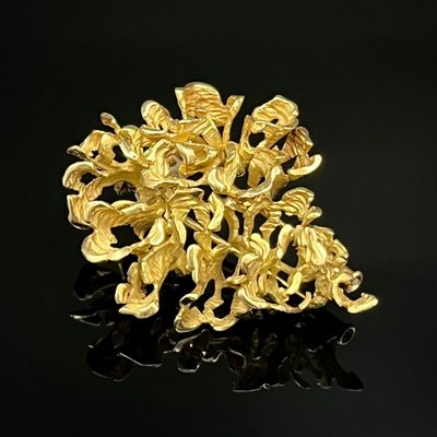 Broche en forme de fleur plaquée or jaune sur fond noir avec reflets