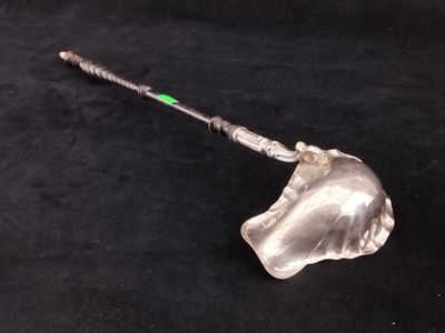 un objet en verre muni d'une poignée métallique posé sur une surface noire
