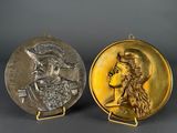 two gold and silver medallions of a man and a woman
