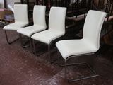 quatre chaises de salle à manger en cuir blanc disposées dans une pièce à côté d'un escalier