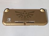 the nintendo wii is sitting on a white surface with a gold case