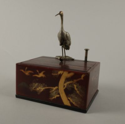 statue d'une grue posée sur une caisse en bois, sur fond blanc