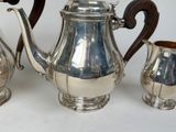 a silver tea pot and two silver cups on a table