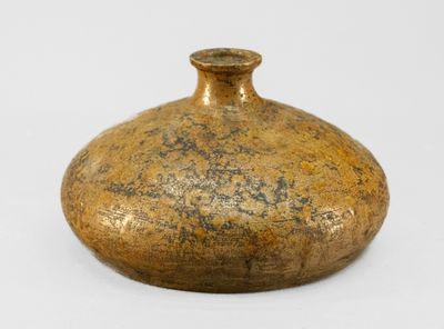 un vase en or posé sur une surface blanche