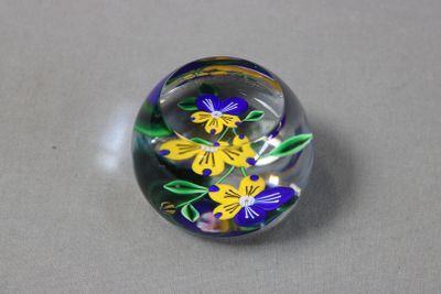 des fleurs jaunes et bleues dans une boule en verre posée sur une surface grise