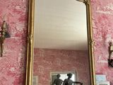 un miroir posé sur une cheminée dans une pièce au papier peint rose