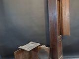 a wooden grandfather clock sitting on the floor next to a small table