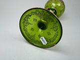 a green vase with a gold rim sitting on a white surface