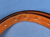 a close up of a brown leather belt on a blue surface