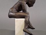 statue of a man sitting on a block with his head on his hands