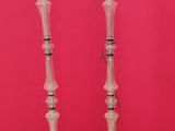 a pair of glass candlesticks on a tripod stand