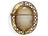 an image of a gold broochle with a white stone in it