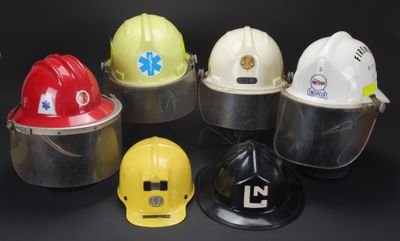 six casques de chantier sont alignés sur un fond noir