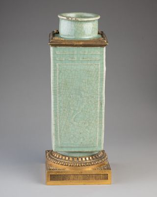 une image représentant un vase vert posé sur un socle en bois