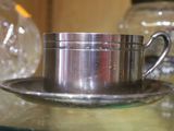 une tasse et une soucoupe en argent posées sur une table en verre