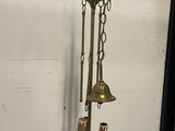 a brass clock hanging on a wall next to a black curtain