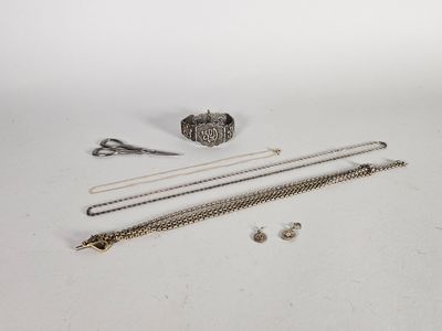 des bijoux en argent sur fond blanc, avec une paire de ciseaux et un bracelet