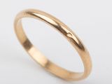 a gold wedding ring with a thin band on a white background
