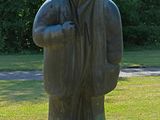 a statue of a man with a hood on in the grass