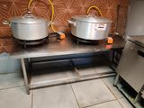 des casseroles et des poêles posées sur une table dans une cuisine avec du papier peint