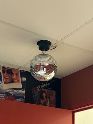 a disco ball hanging from the ceiling above a bed