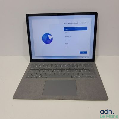 un ordinateur portable ouvert posé sur une table blanche