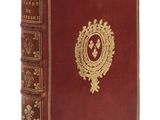 un vieux livre rouge aux tranches dorées et orné d'un emblème doré sur la couverture
