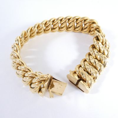 gros plan d'un bracelet en or sur une surface blanche