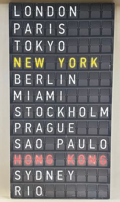 un panneau sur lequel on peut lire : Londres, Tokyo, New York, New York, Manhattan, Stockholm, Prague, Hong, Hong, Rio