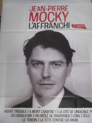 affiche représentant un homme en costume-cravate, assis à une table