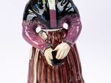 une figurine représentant une femme en robe et chapeau