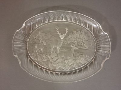 une assiette en verre sur laquelle est représenté un cerf, posée sur une table