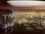 bottles and glasses are lined up on a shelf in a kitchen