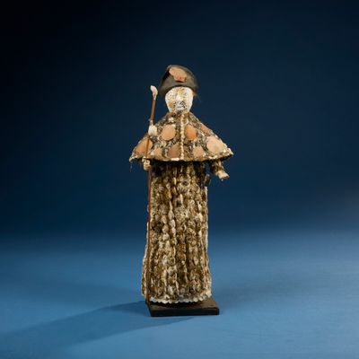 statue d'une femme vêtue d'un manteau de fourrure et d'un chapeau, tenant un bâton