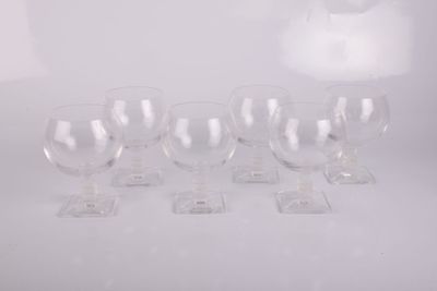 six verres à vin transparents posés sur une table blanche