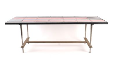 La table est en métal et son plateau est recouvert de carreaux colorés.