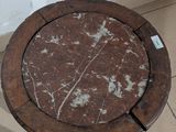 a marble top table with a wooden base on a tiled floor