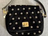 une photo d'un sac à main noir orné d'étoiles argentées