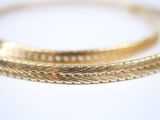 two gold bracelets on a white surface with a white background
