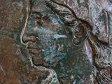a close up of a bronze coin with a woman on it