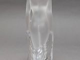 a glass sculpture of a woman sitting on a table