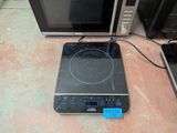 a black stove top with a blue burner on top of it next to a microwave oven