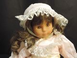 a doll that is wearing a pink dress and a hat