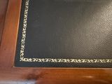 an old black book with gold trim sitting on top of a wooden table