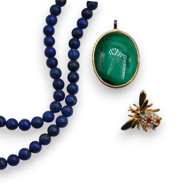 a close up of a necklace and a broochle on a white surface