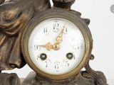 a statue of a woman holding a clock on a table