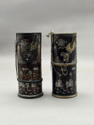une paire de vases noirs et dorés posés sur une surface blanche